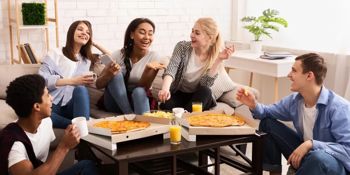 Studenti jedí pizzu a povídají si.